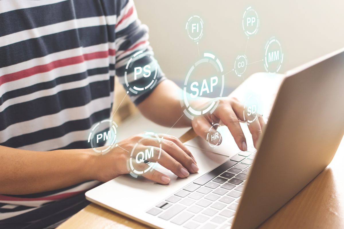 agilux-liaison-erp Personne utilisant un ERP sur un ordinateur avec des icônes flottantes représentant différents modules, symbolisant la liaison de son erp avec ses outils digitaux.