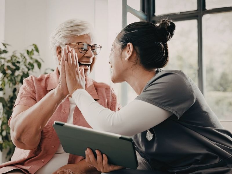 Infirmière à domicile tenant une tablette en main pour renseigner les infos de sa patiente sur son ERP médical