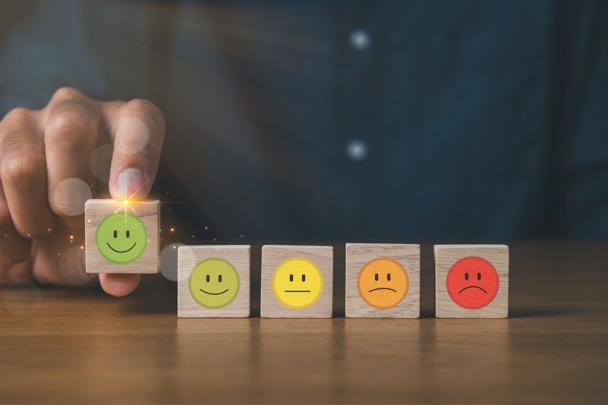 AGILUX-fidelisation-client-1 5 petits blocs en bois avec des smileys allant de fâché à content pour représenter la fidélisation client